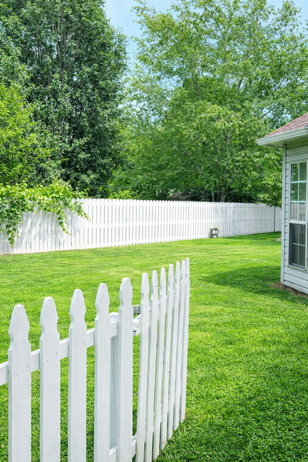 Manicured backyard lawn with white picket fence